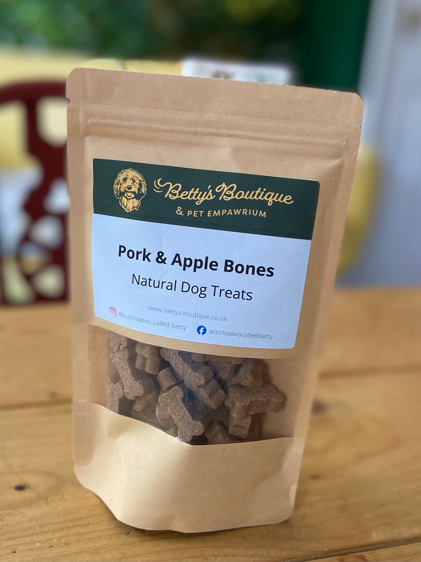 Package of Betty's Boutique Pork & Apple Bones natural dog treats on a wooden surface.