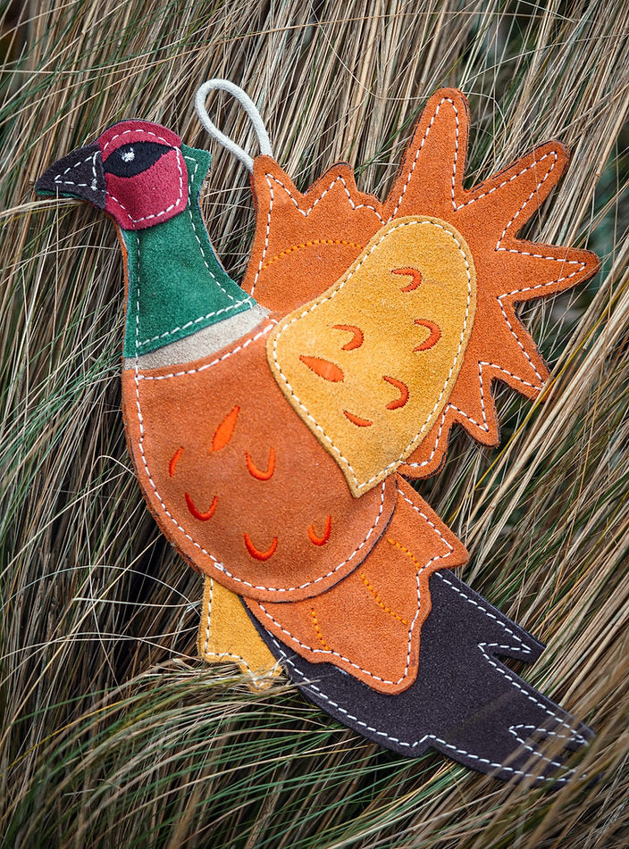 suede pheasant dog toy in grass
