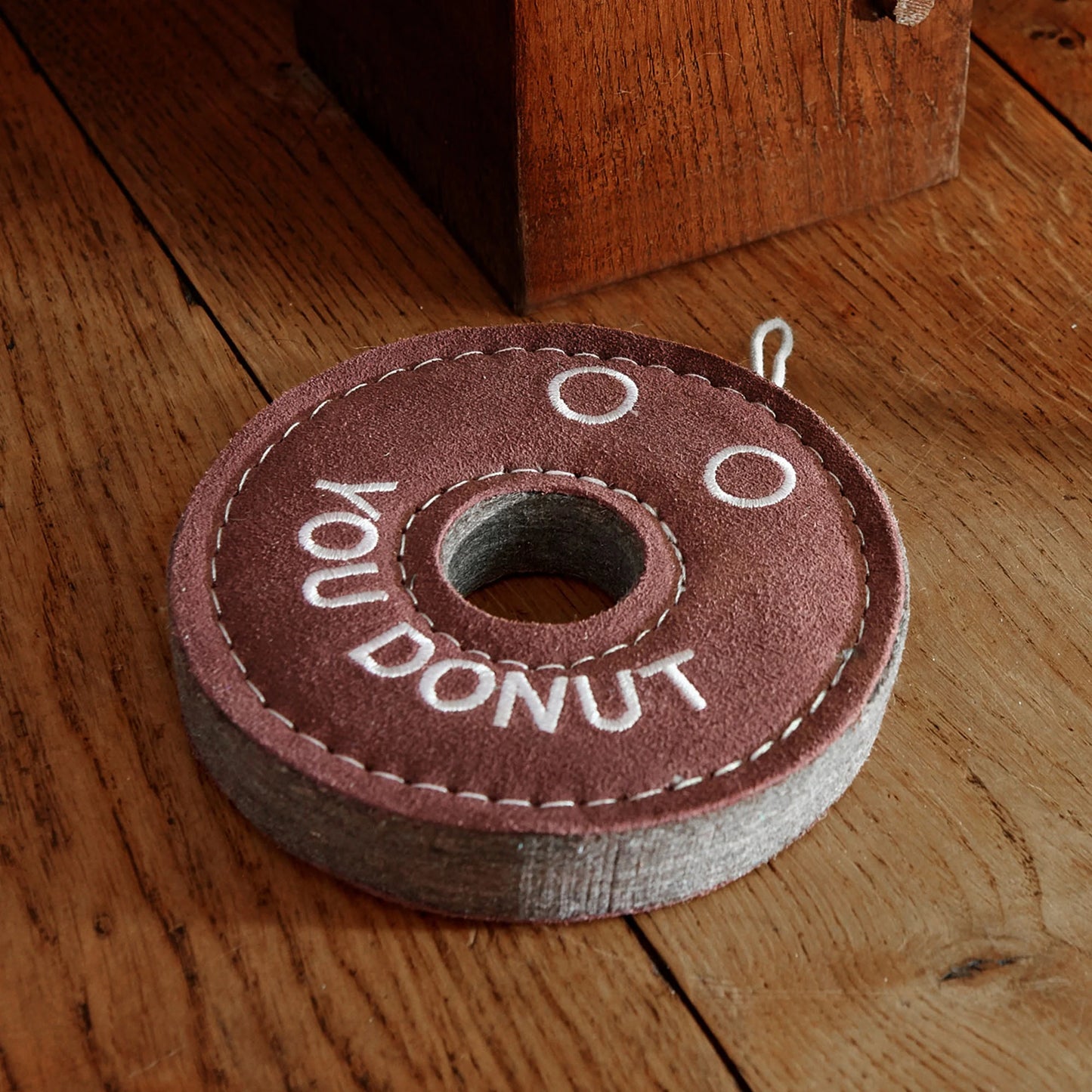 Felt toy shaped like a donut with 'YOU DONUT' text on a wooden floor.
