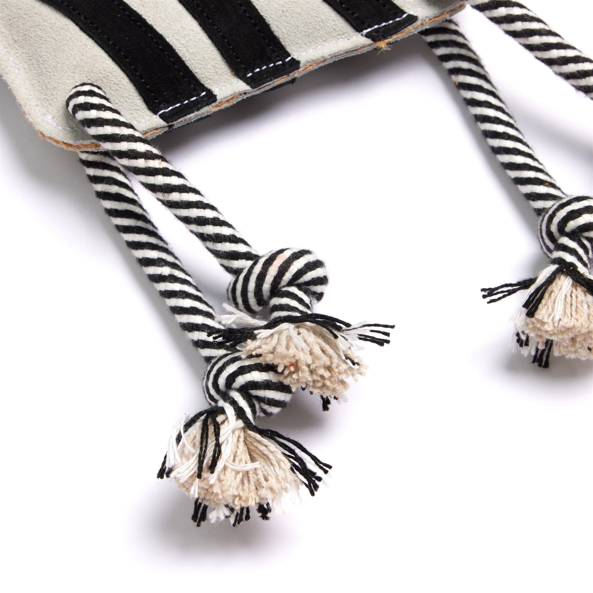 Black and white striped dog toys with pom-poms on a white background